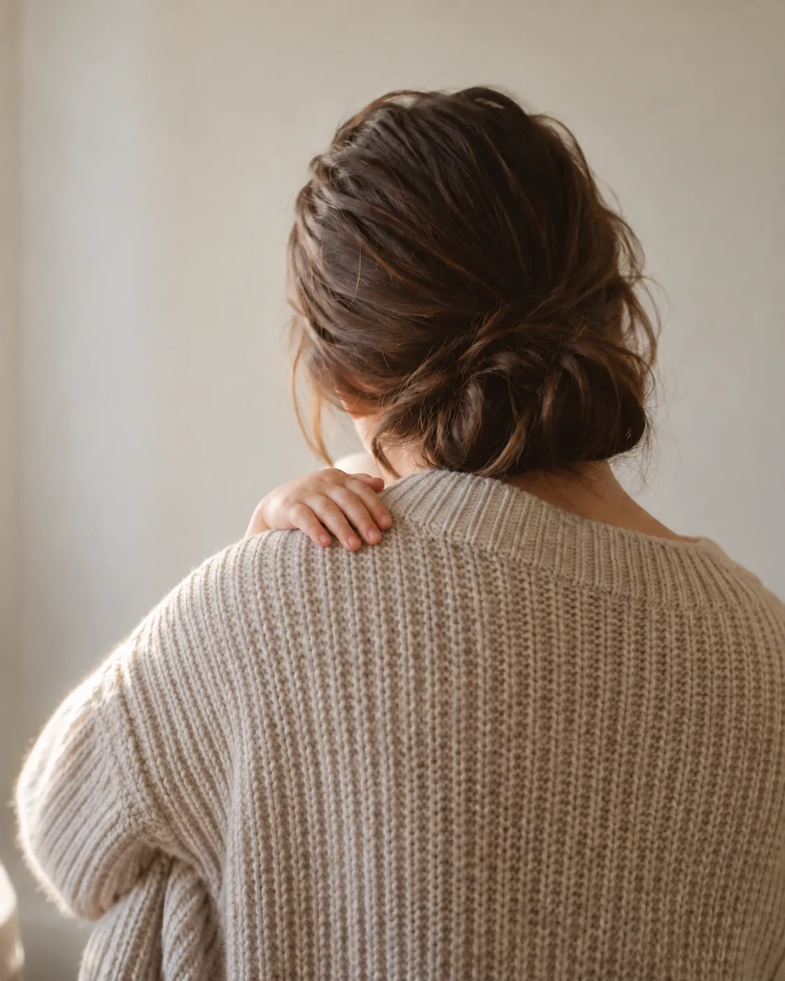 아이를 품에 안은 어른의 등과 어깨, 어깨 위에 얹힌 아이의 작은 손