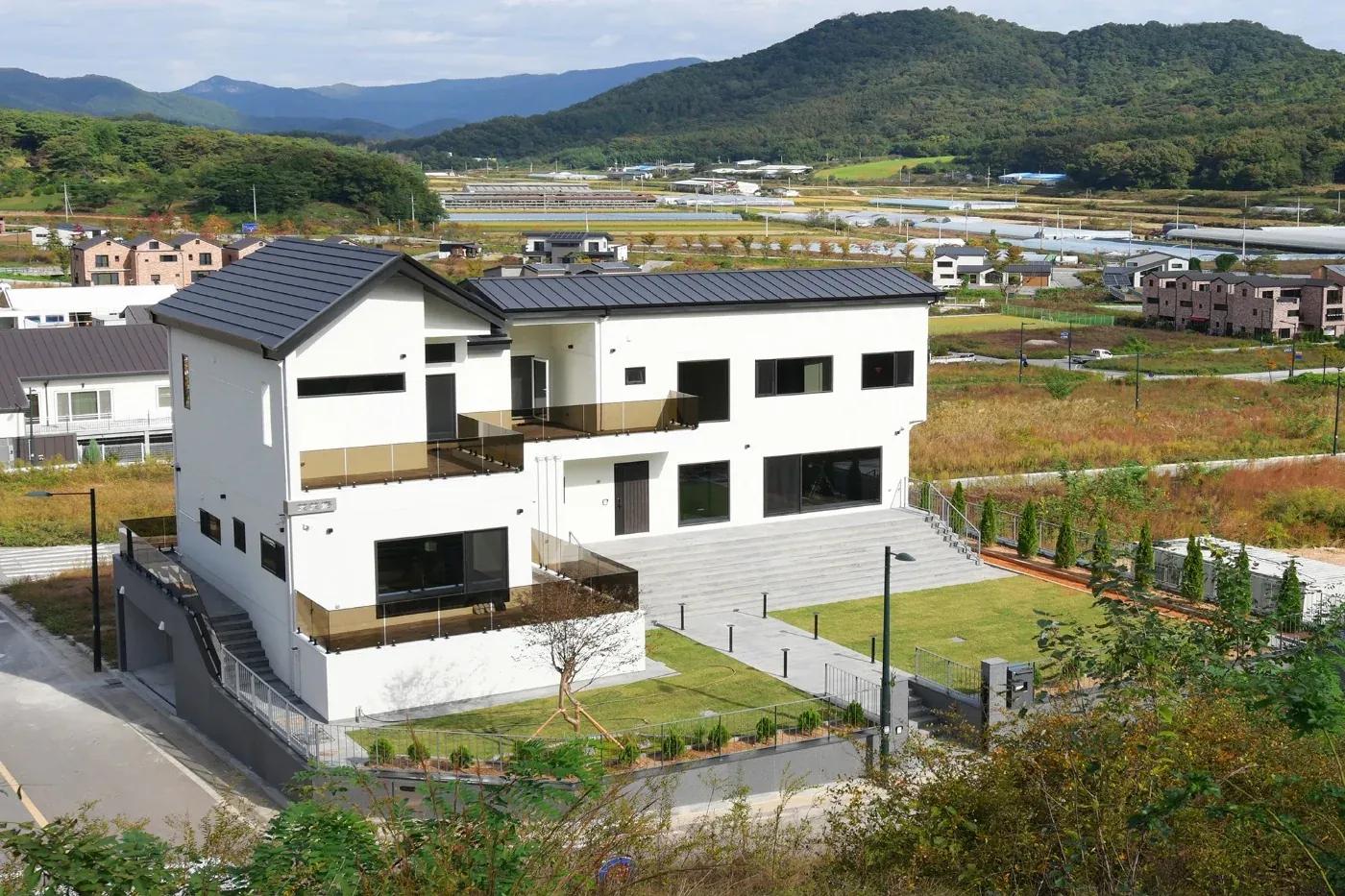 언덕 위에서 마을과 산을 바라보는 소소재 전경